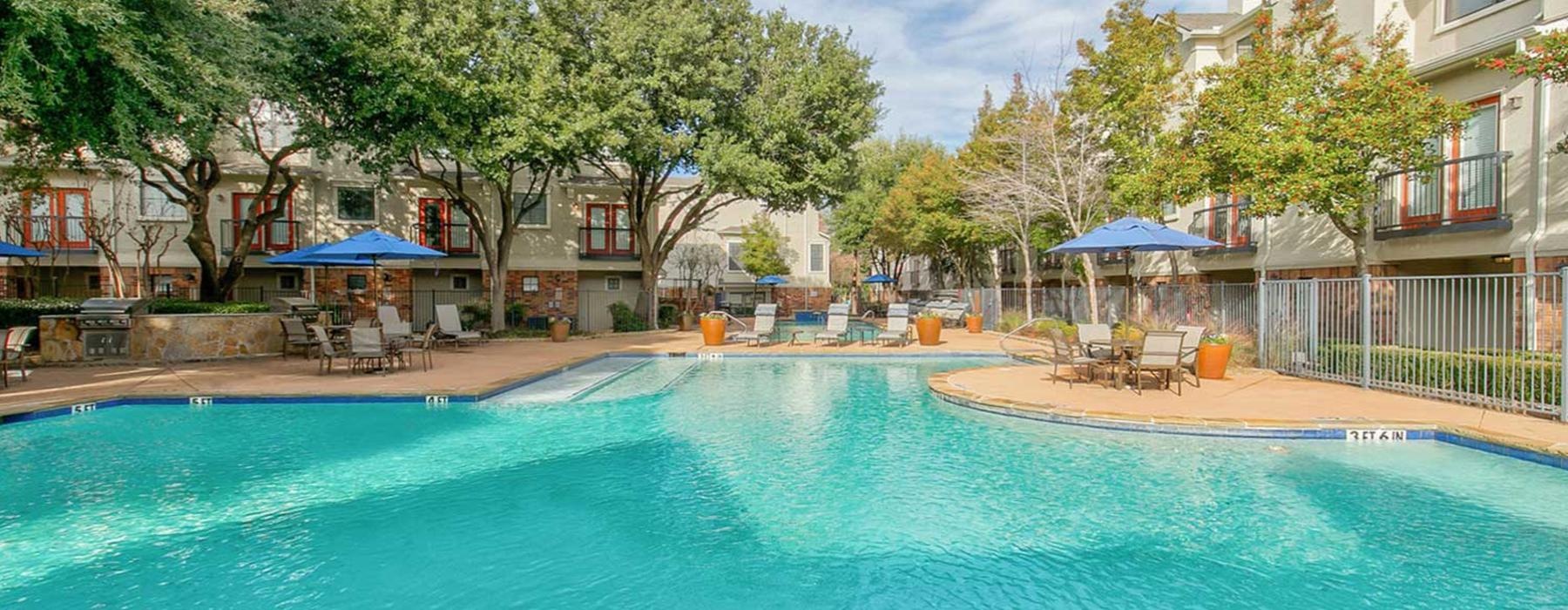a swimming pool with chairs and umbrellas by a building