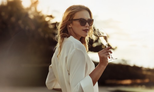 a woman with sunglasses sipping on wine outdoors